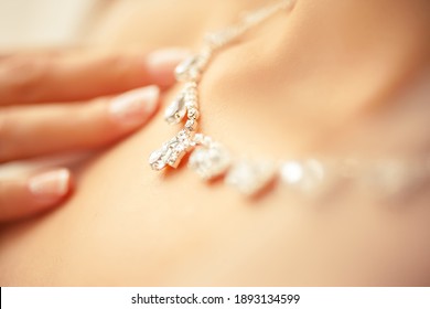 Female hand touching a necklace. Close up focus concept.