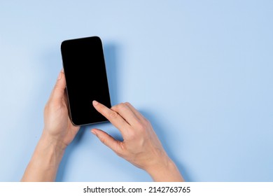 Female Hand Touching Smartphone Display And Pointing With Index Finger On Blank Mobile Phone Screen On Light Blue Background