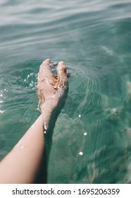 Female Hand Touching Water In Sea