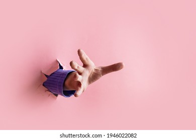 female hand trying to catch something sticking out from pink background  - Shutterstock ID 1946022082