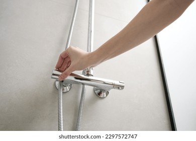 Female hand turn on shower faucet. Modern shower set in bathroom interior. Hygiene concept - Shutterstock ID 2297572747