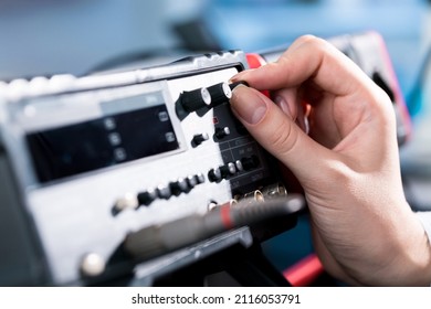 female hand twists a potentiometer on a functional signal generator in a radio engineering laboratory