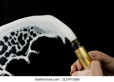 Female hand uncorks bottle of champagne on black studio background. Explosion of sparkling white wine with foam and bubbles. Festive background, holiday, celebrating new year, birthday party. Close up