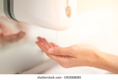 Female hand use the automatic alcohol dispenser in front of the public area , Coronavirus infection or COVID-19 outbreak prevention all around the world. - Powered by Shutterstock