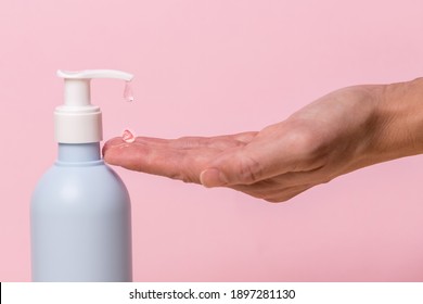 Female Hand Using Alcohol Gel Sanitizer Bottle Dispenser, Against Coronavirus Disease (Covid-19) . Antiseptic, Hygiene And Health Concept. Minimalist Style On Pink Background