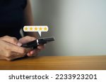 Female hand using smartphone with five star popup icon satisfaction survey concept business customer service.
