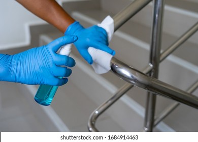 Female hand using wet wipe and alcohol sanitizer spray to clean stainless steel staircase railing.Antiseptic,disinfection ,cleanliness and heathcare, Anti Corona virus (COVID-19). Selective focus.