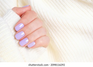Female hand with violet manicure isolated on white knitted background.