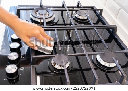 Female hand washing gas stove with sponge, house cleaning concept