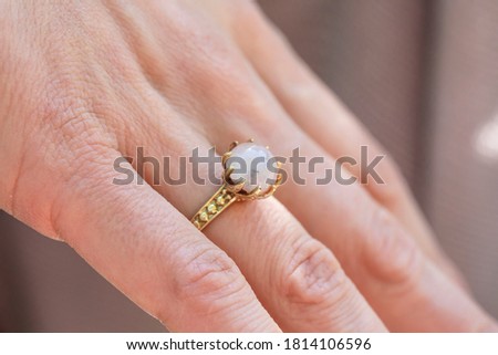 Female hand wearing brass ring with shiny moonstone gemstone