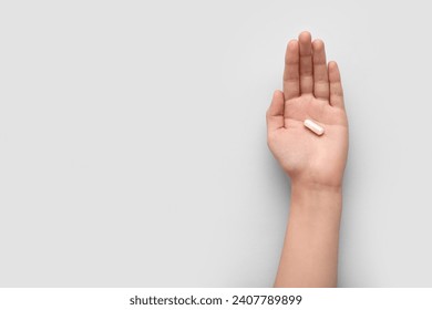 Female hand with white capsule on light background - Powered by Shutterstock