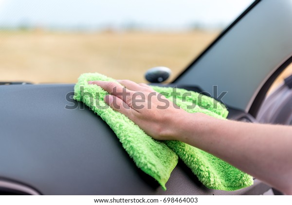 A female hand wipes the panel of a modern auto\
rag with a microfiber from\
dust