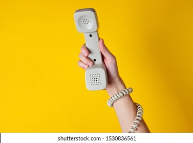 Female Hand Wrapped In Cable Holds Phone Tube Against Yellow Background. Port Art. Creative Minimalism. Top View