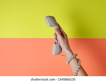 Female Hand Wrapped In Cable Holds Phone Tube Against Colored Background. Port Art. Creative Minimalism. Top View