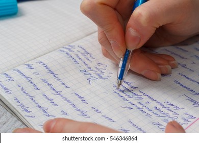 female hand writes a blue pen in a notebook in a cage