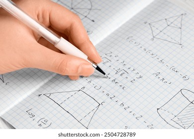 Female hand writing maths formulas in copybook, closeup - Powered by Shutterstock