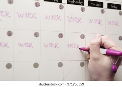 Female Hand Writing On Calendar White Board Filled With Busy Work Schedule. 