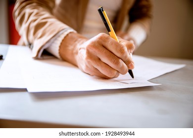 Female hand writing signature on the paper document. Cut out Woman signs agreement or formulary contract. Paperwork concept