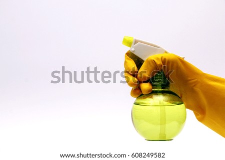 A female hand in a yellow latex glove holds a bottle of detergent on the white background
