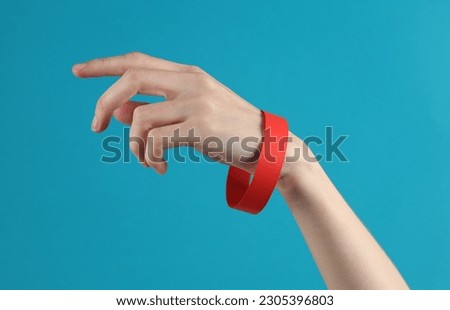 Female hand with a yellow paper bracelet on a blue background