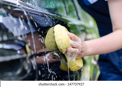 Female Hand With Yellow Sponge Washing Car