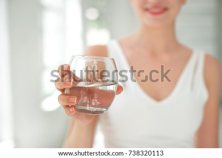 Female handa holding a clear glass of water. Slime body on background.