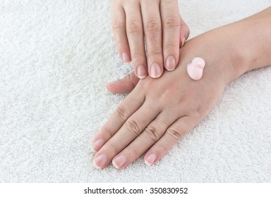 Female hands applaing a cream on fabric background
