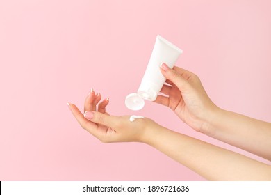 Female Hands Apply Cosmetic Skin Care Moisturizer Cream On Pink Background