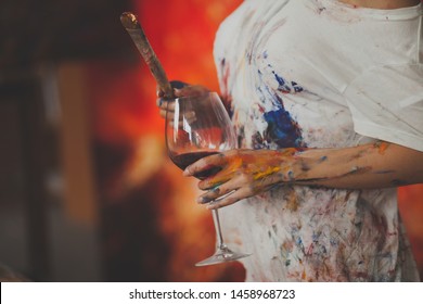 
female hands of the artist with glass of wine, brushes, paints, and a palette for drawing