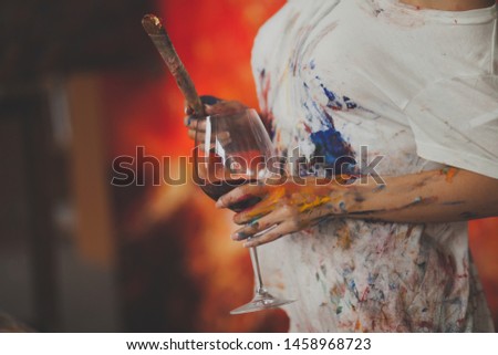 
female hands of the artist with glass of wine, brushes, paints, and a palette for drawing