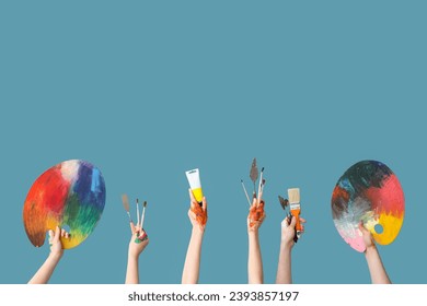 Female hands with artist's supplies on blue background - Powered by Shutterstock