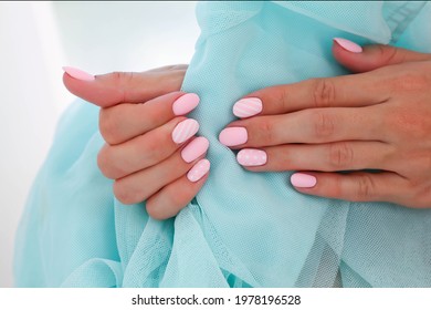 Female hands and beautiful oval  shaped nails  matte pink manicure close  up blue background  Shellac  Copy space