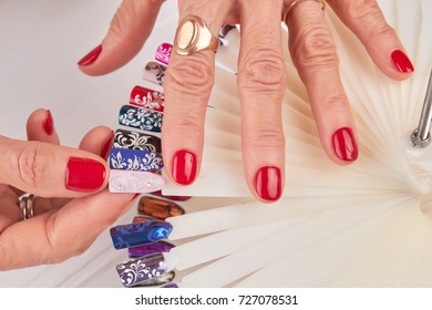 Female Hands With Beautiful Red Manicure. Close Up Of Old Woman Manicured Hands Holding Nail Color Art Samples. Woman In Nail Salon.