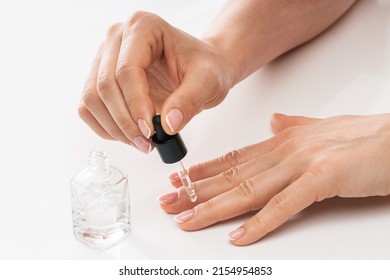 Female Hands And Bottle Of Nourishing Cuticle Oil With A Dropper On White Background 