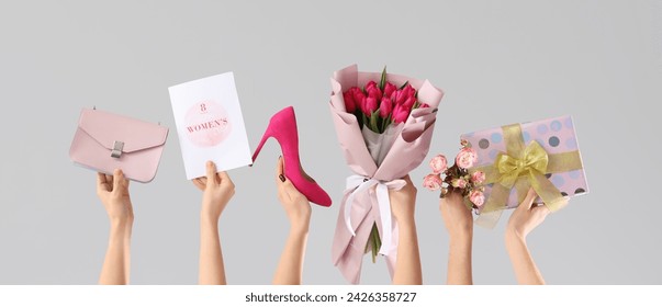 Female hands with bouquet of tulips, gift, shoe and handbag on grey background. Shopping for International Women's Day