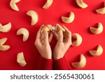 Female hands with broken fortune cookie on red background