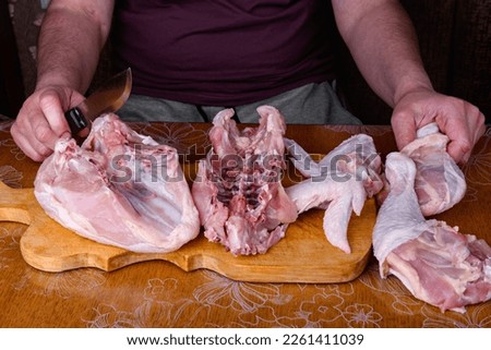 Female hands carves a whole chicken carcass on a wooden board.