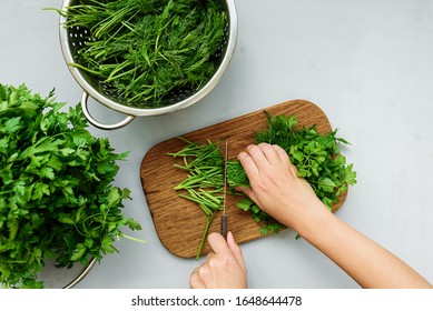 Female hands chopping fresh green parsley and dill  (fennel) on cutting boar on gray wooden table. Top view. Copy space. Harvesting concept - Powered by Shutterstock