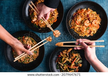 female hands with chopsticks close-up eating Thai food, salads and wok, asian food, top view. Chinese and vietnamese cuisine set.