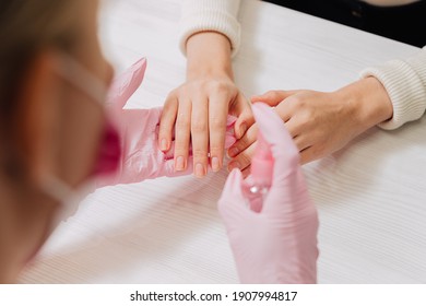 Weibliche Hände, Nahaufnahme. Hände in rosafarbenen Gummihandschuhen behandeln die Haut der Hände mit einem Antiseptikum.