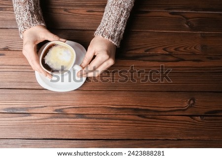 female hands and coffee on wooden background