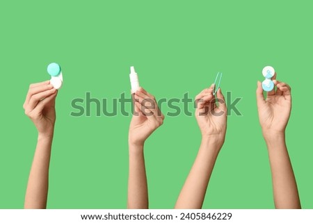 Female hands with containers for contact lenses, tweezers and eye drops on green background. Glaucoma awareness concept