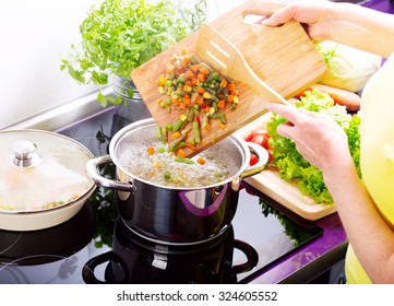 female hands cooking vegetable soup in the kitchen