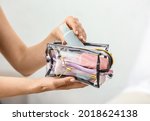 Female hands and cosmetics bag on light background