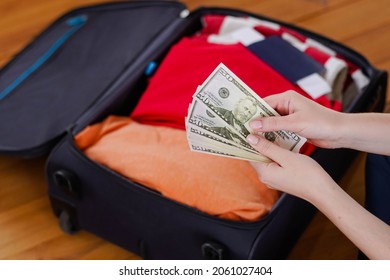 Female hands counting dollar cash banknotes on suitcase background. Woman travel after open boarders.