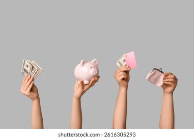 Manos femeninas con tarjeta de crédito, dinero, cartera y hucha sobre fondo gris