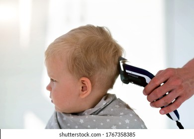 Female Hands Cut A Child With A Hair Clipper In A Hairdresser. The First Haircut. Mom Cuts A Boy During Quarantine