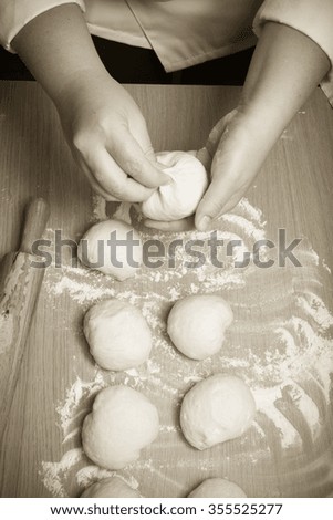 Female hands cut up dough. Selective focus. Toned.