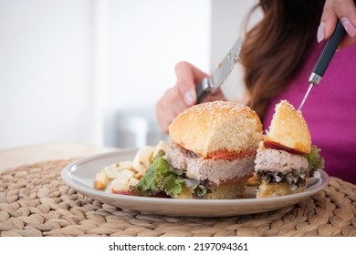 Female Hands Cut Hamburgers In Half, Fast Food Concept In The House.