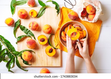 Female hands cutting fresh sweet peaches. Peaches whole fruits leaves, half peach, peach slices on white wooden kitchen table. Recipe making peach jam, cooking peach dessert on cutting board. Flat lay - Powered by Shutterstock